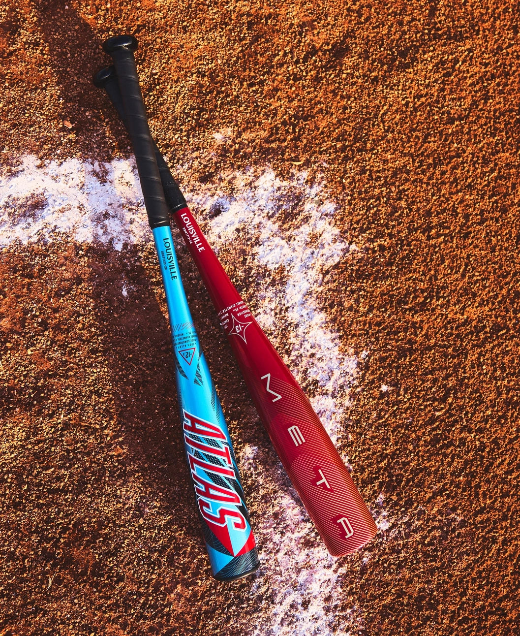 Two baseball bats with 'Atlas' branding on a dirt field.