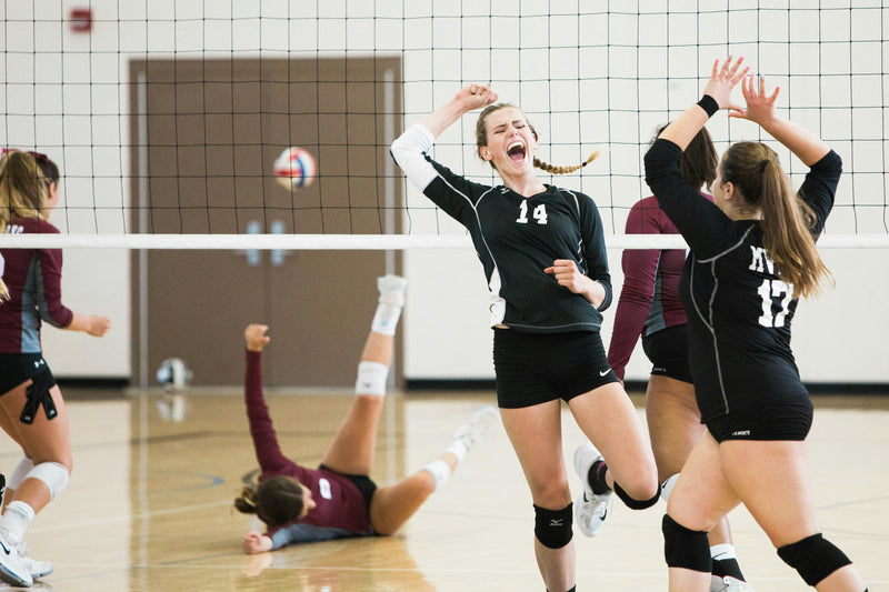 Volleyball players going up at the net during a match